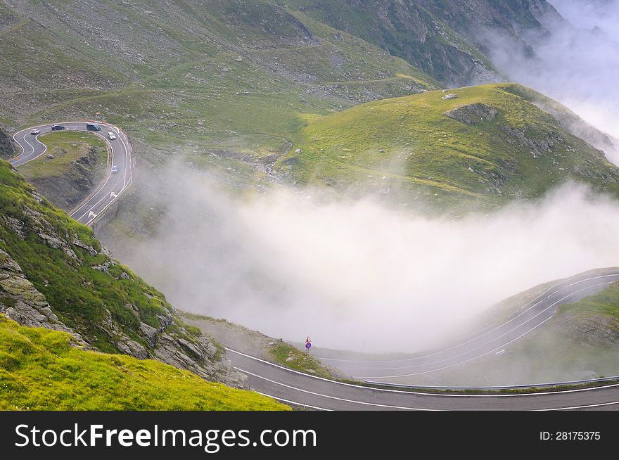 View of serpentin mountain road with green grass and fog. View of serpentin mountain road with green grass and fog.