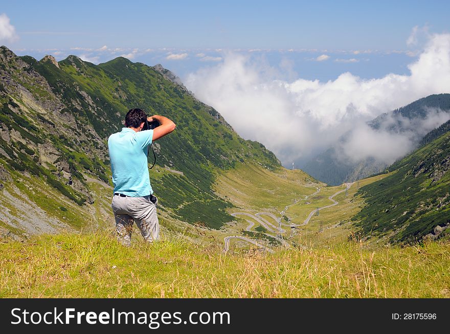 Tourist taking pictures of breathtaking scenery from mountain top. Tourist taking pictures of breathtaking scenery from mountain top.