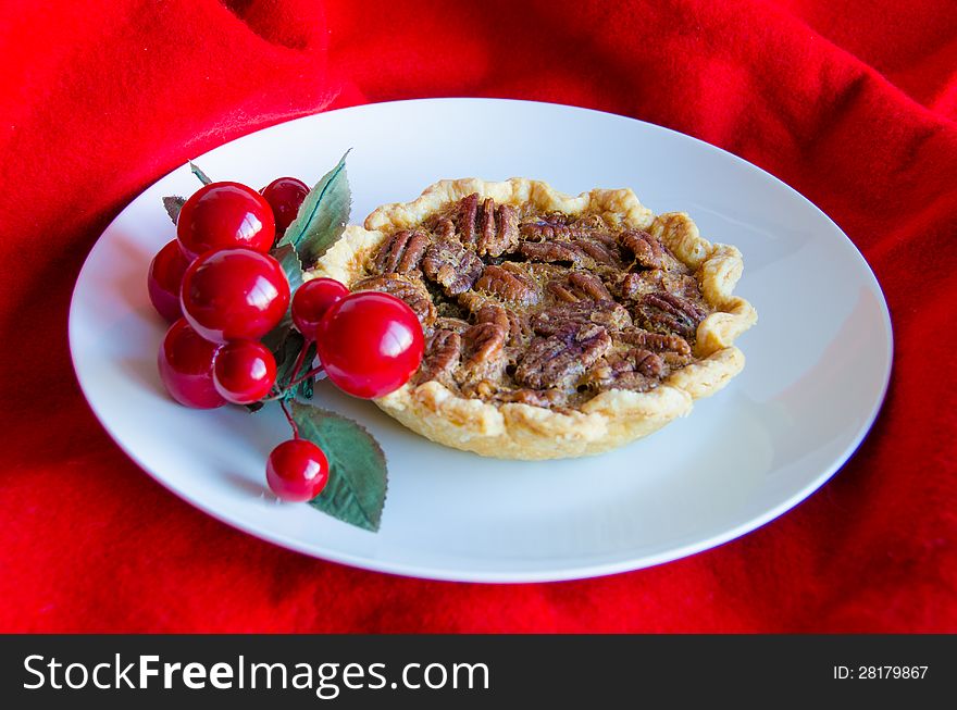 Christmas pecan tart decorated with artificial red cherries with a red fabric background. Christmas pecan tart decorated with artificial red cherries with a red fabric background.