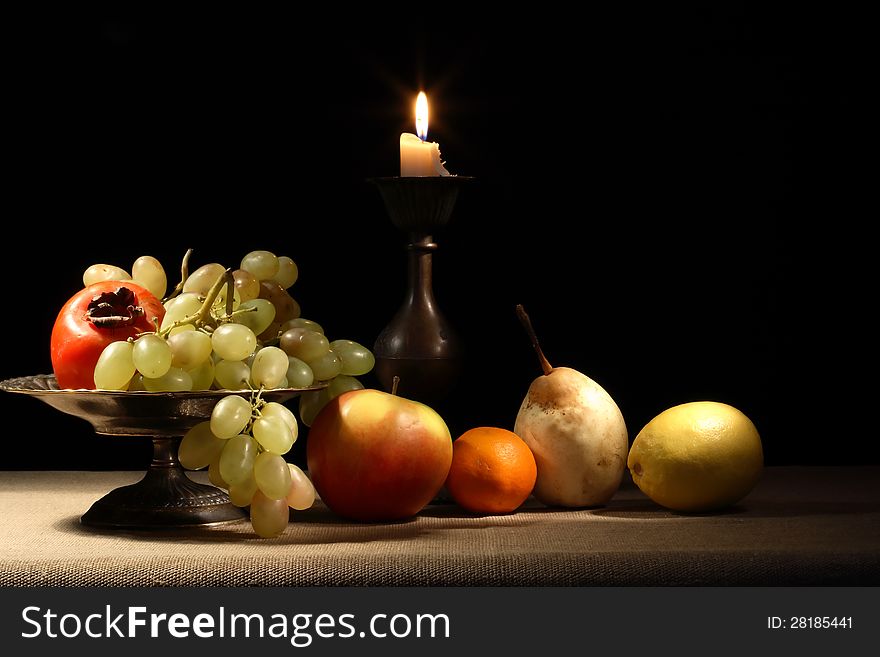 Vintage still life with fruits in bowl near lighting candle. Vintage still life with fruits in bowl near lighting candle