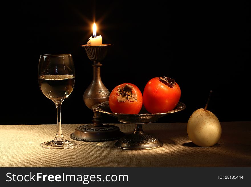 Vintage still life with fruits in bowl and wineglass near lighting candle. Vintage still life with fruits in bowl and wineglass near lighting candle