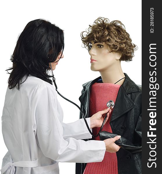 Young woman is examining the chest of the mannequin. She is wearing a white doctor's smock and using a stethoscope. Young woman is examining the chest of the mannequin. She is wearing a white doctor's smock and using a stethoscope.