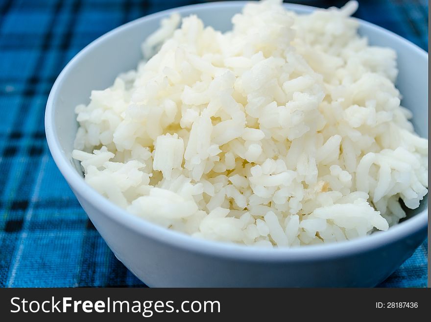 Thai jasmine rice in blue dish, on blue Plaid tablecloth.