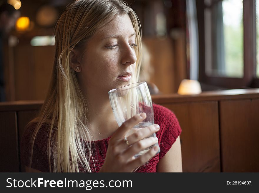 Young woman drinking water at a pub