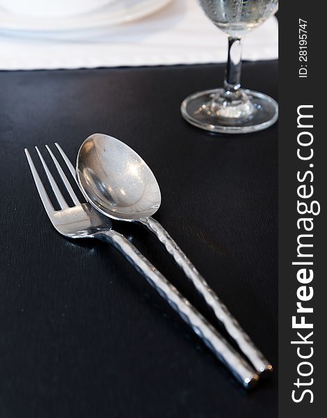 Silver spoon and fork on black table. Silver spoon and fork on black table