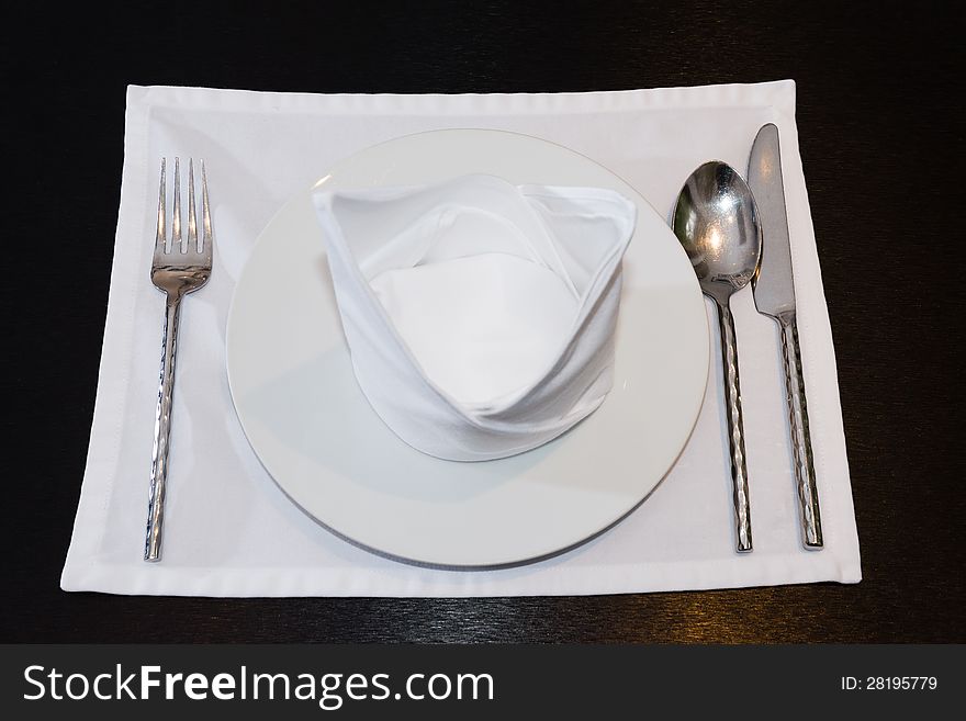 White napkins folded as triangles on plates with silverware set on the table