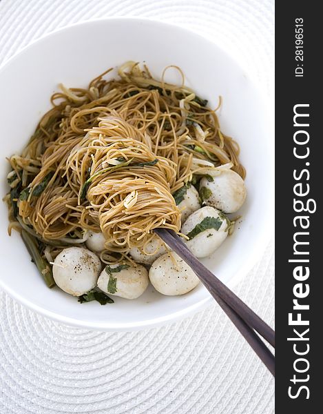 Asian noodle on chopsticks in white bowl