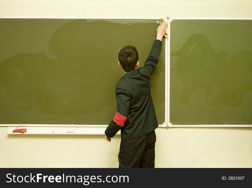 A young pupil is cleaning the blackboard. A young pupil is cleaning the blackboard