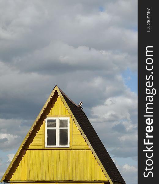 Wooden cottage fragment against sky with clouds