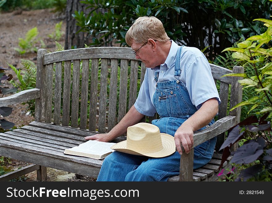 An older man studying the Bible outside on a bench. An older man studying the Bible outside on a bench.