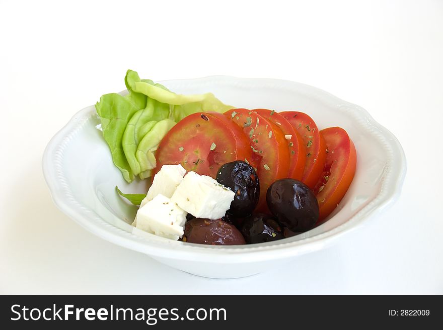 A bowl with vegetables salad: tomato, lettuce, olive, cheese. A bowl with vegetables salad: tomato, lettuce, olive, cheese