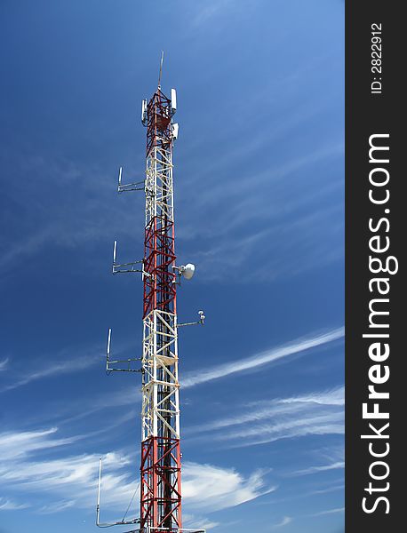 Antenna of telecomunications under a blue cloudy sky