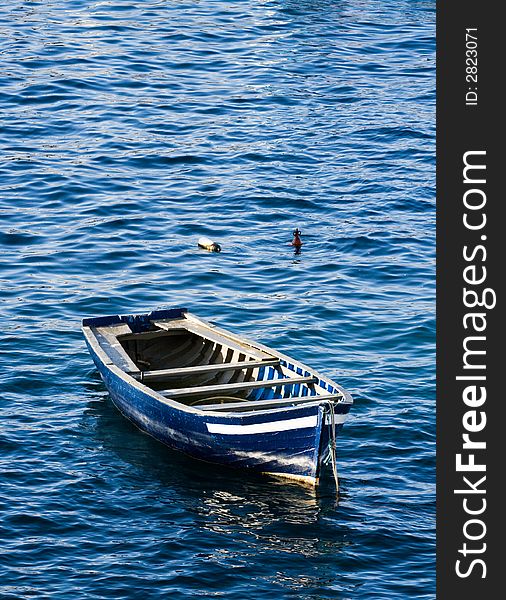 Wooden fishing boat floating on the blue sea. Wooden fishing boat floating on the blue sea