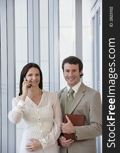 Smiling modern business couple with woman on cell phone