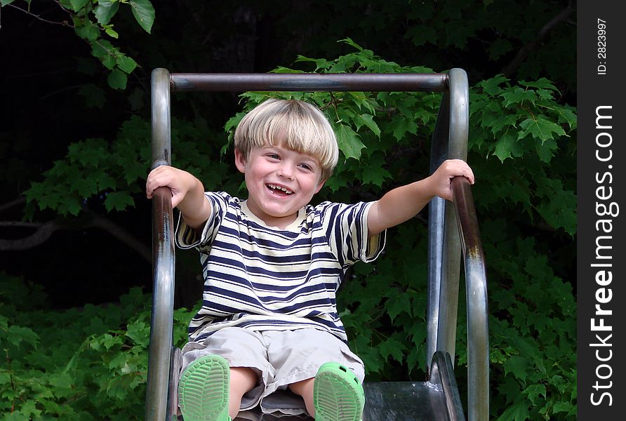 Young boy smiling on slide at playground