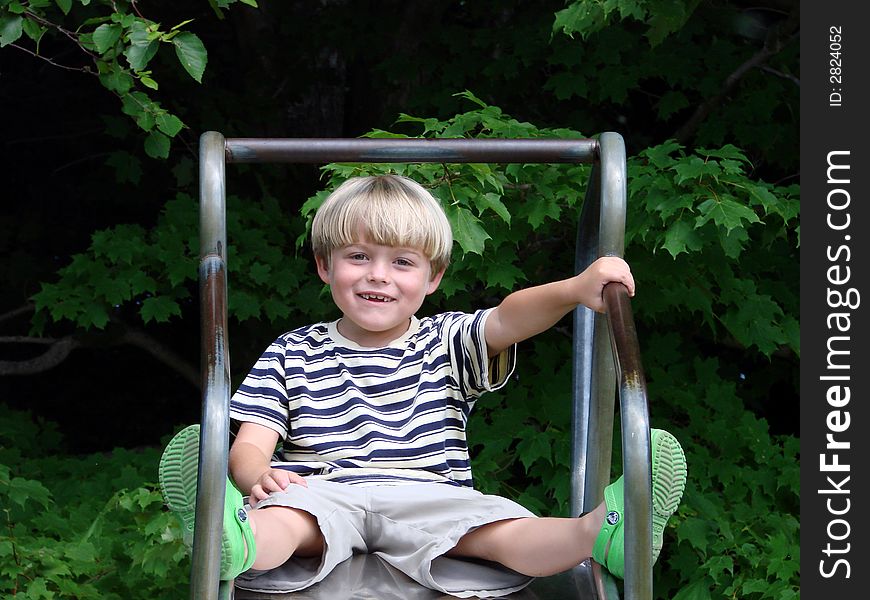 Young boy smiling on slide at playground