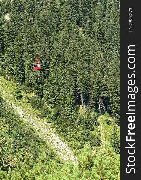 Transportation: a red cable-car cabin through the forest. Transportation: a red cable-car cabin through the forest