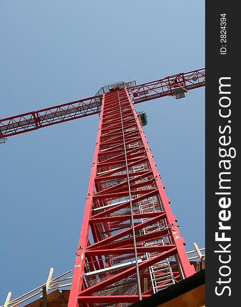 A bright red construction crane rising into the sky. A bright red construction crane rising into the sky