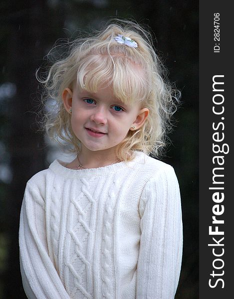 Pretty six year old blond girl looking shyly at the camera while standing outside. Pretty six year old blond girl looking shyly at the camera while standing outside.