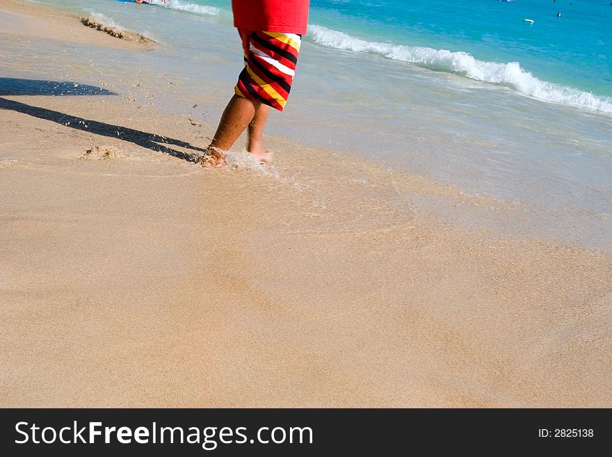 Person walking into the ocean surf from the sandy beach. Person walking into the ocean surf from the sandy beach