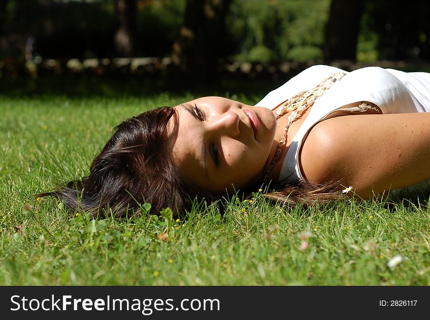 Attractive woman lying and relaxing on green grass. Attractive woman lying and relaxing on green grass