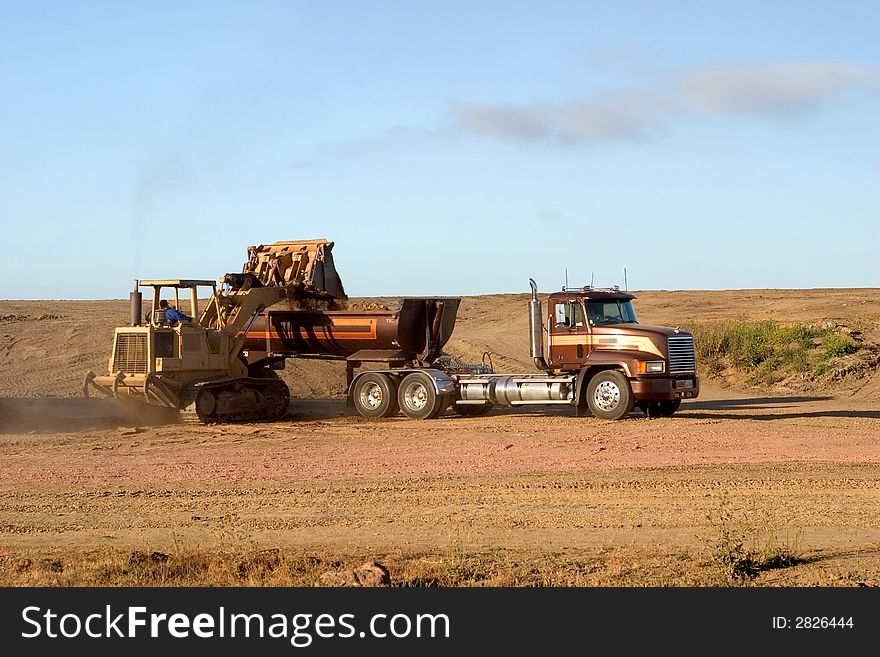 A scoop loader and a truck working at groundworks