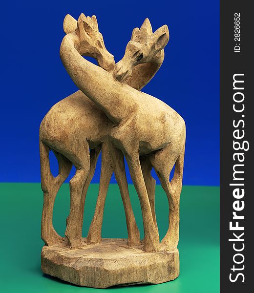 Wooden carving of two giraffes commonly found on roadsides in africa (curios) against a blue and green background. Wooden carving of two giraffes commonly found on roadsides in africa (curios) against a blue and green background.