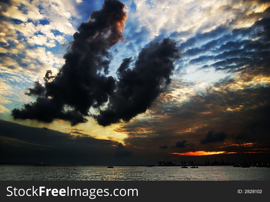 Two huge chunks of dark clouds dominate the foreground of a dramatic sunset. Two huge chunks of dark clouds dominate the foreground of a dramatic sunset