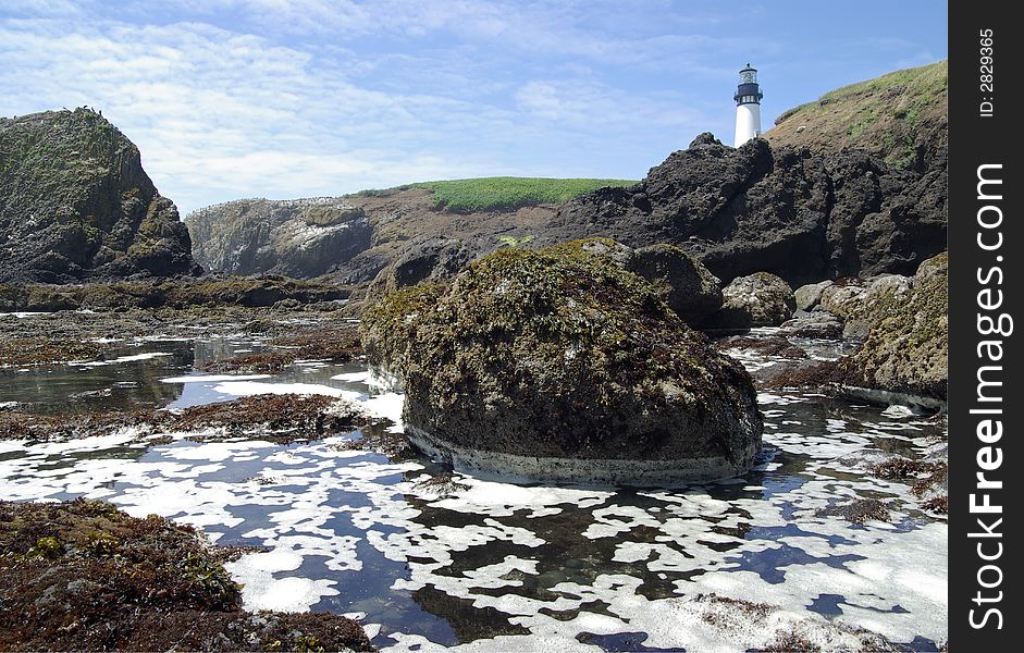 Lighthouse with blue sky, rocks and tide pools, horizontal. Lighthouse with blue sky, rocks and tide pools, horizontal.