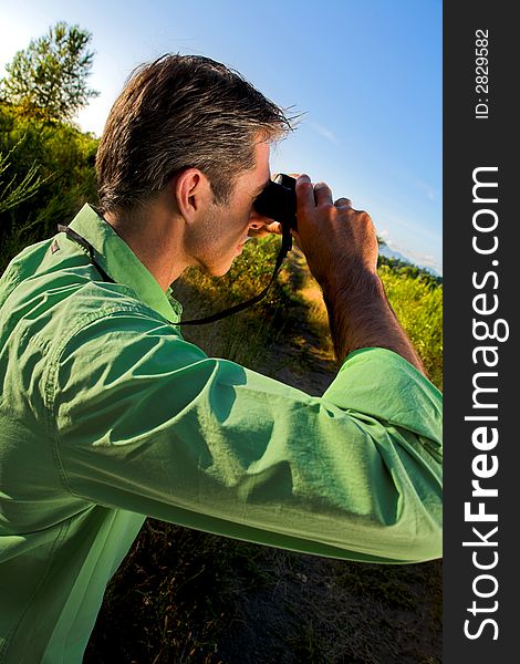 Man using binocular outdoor over blue sky