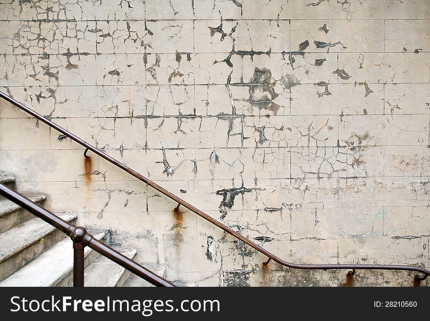 Detail of rusty handrail and wall with peeling paint in an old stairwell