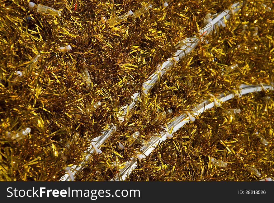 Yellow tinsel Christmas decoration background texture with white bulbs