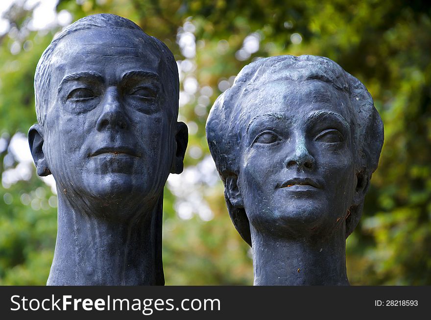 Bronze sculpture of a couple on a green vegetal background