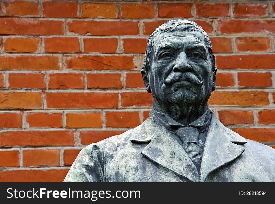 Sculpture of a serious man with moustache on a red bricks wall background. Sculpture of a serious man with moustache on a red bricks wall background