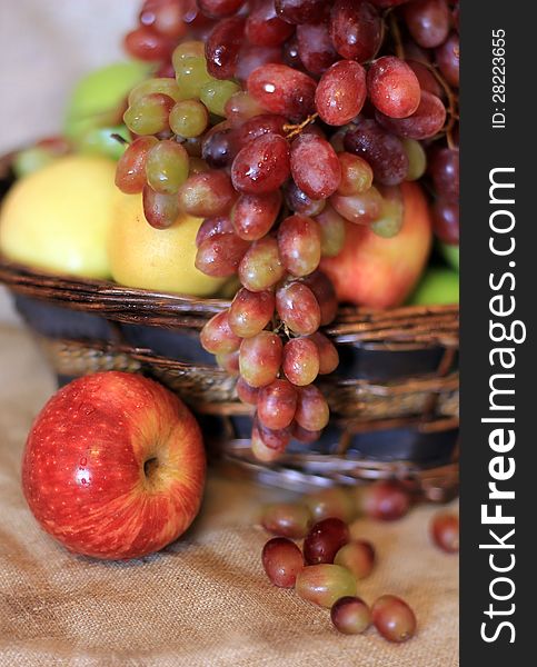 Fresh fruits with water drops in the basket on the tablecloth from canvas. Fresh fruits with water drops in the basket on the tablecloth from canvas