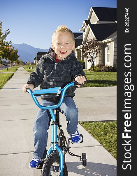Little boy learning to ride a bike with training wheels