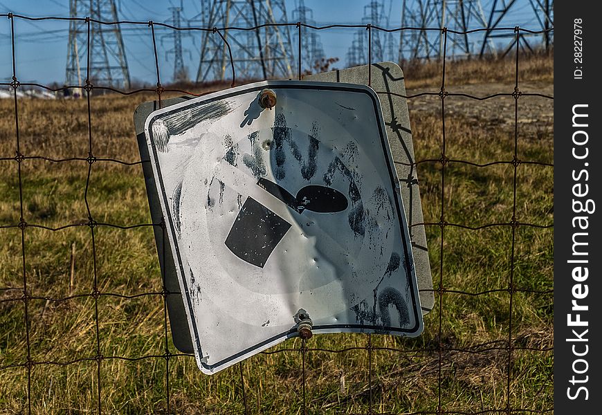 A old no Dumping sign on a fence near a power plan