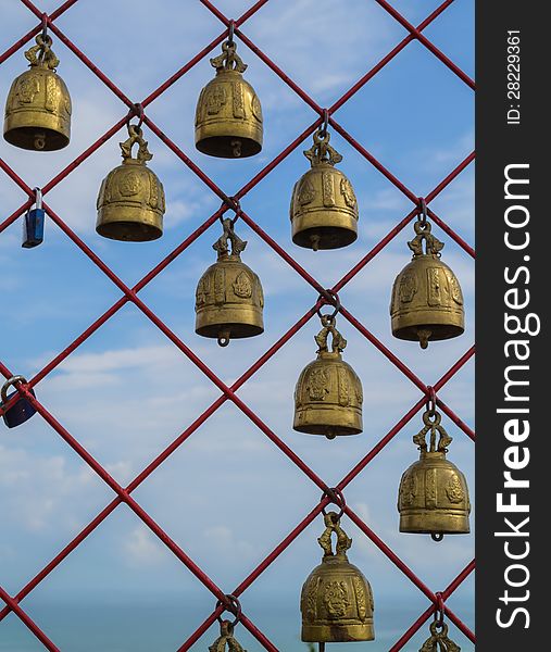 Many of holy bells are hanging on the red net in a buddhist temple
