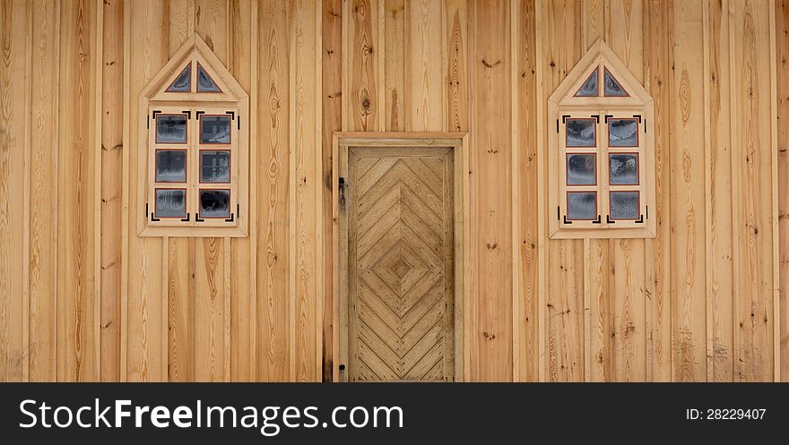 Front of wooden house with door and a pair of windows
