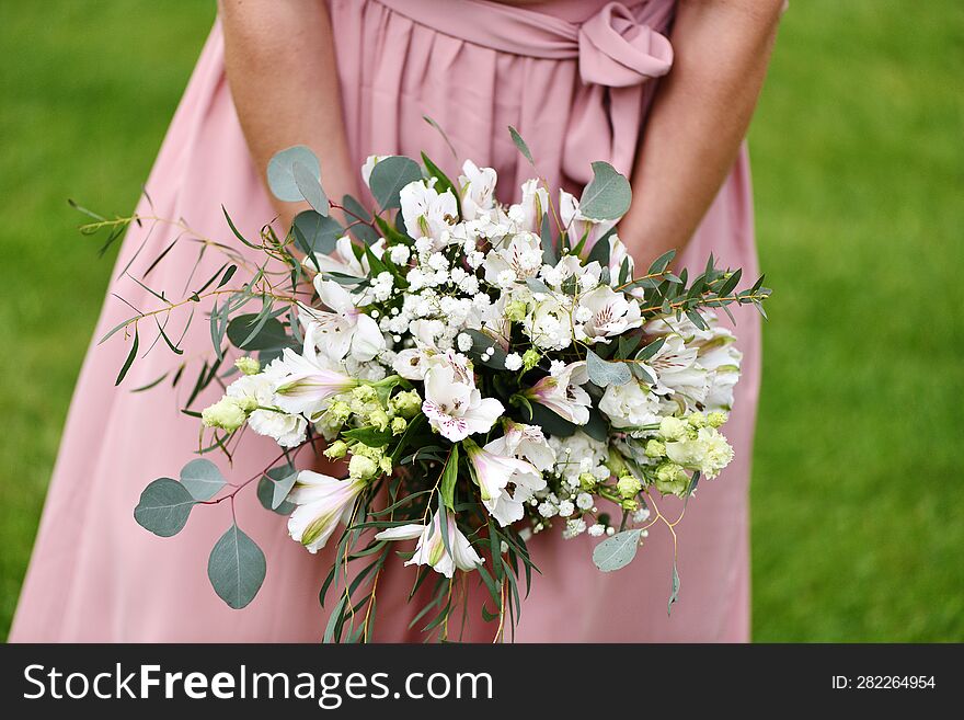 a young girl in a pink dress holds a bouquet of white flowers in her hand. a young girl in a pink dress holds a bouquet of white flowers in her hand