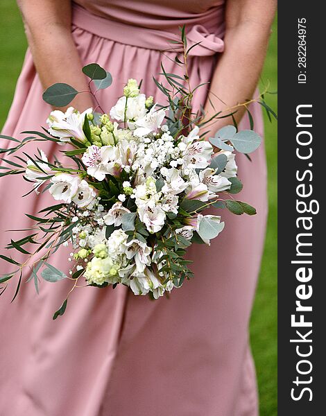 a young girl in a pink dress holds a bouquet of white flowers in her hand. a young girl in a pink dress holds a bouquet of white flowers in her hand