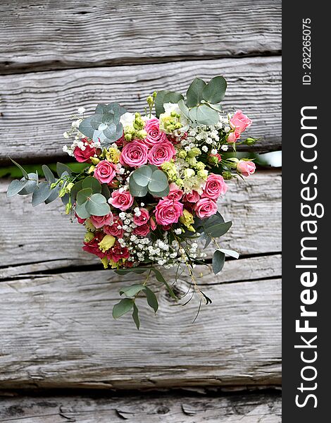 large bouquet of pink roses with white flowers and eucalyptus on a wooden table