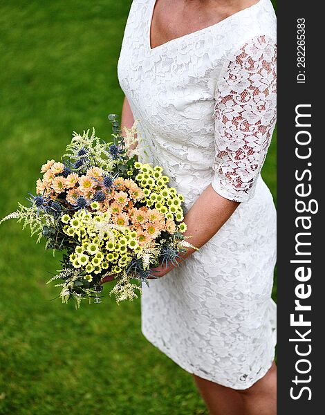 the bride holds a large bouquet of yellow and orange meadow flowers with eucalyptus