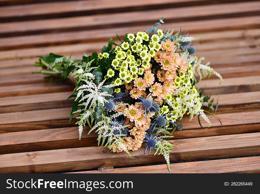 A Large Bouquet Of Yellow And Orange Meadow Flowers On A Wooden Table