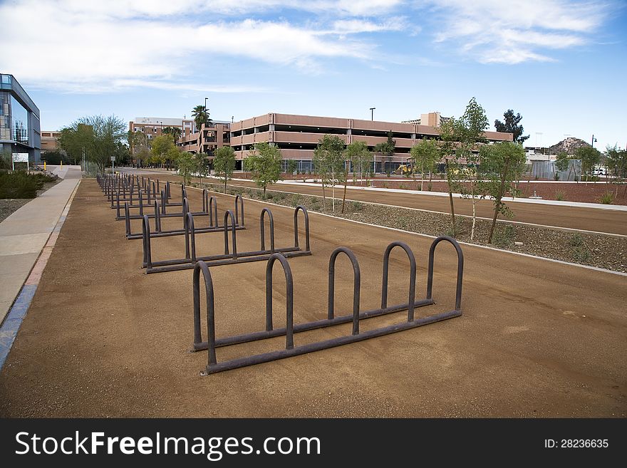 Empty Row of bike racks adjacent to light rail and campus