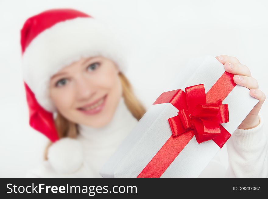 Happy young woman holds out a Christmas present, white gift with a red ribbon. Happy young woman holds out a Christmas present, white gift with a red ribbon