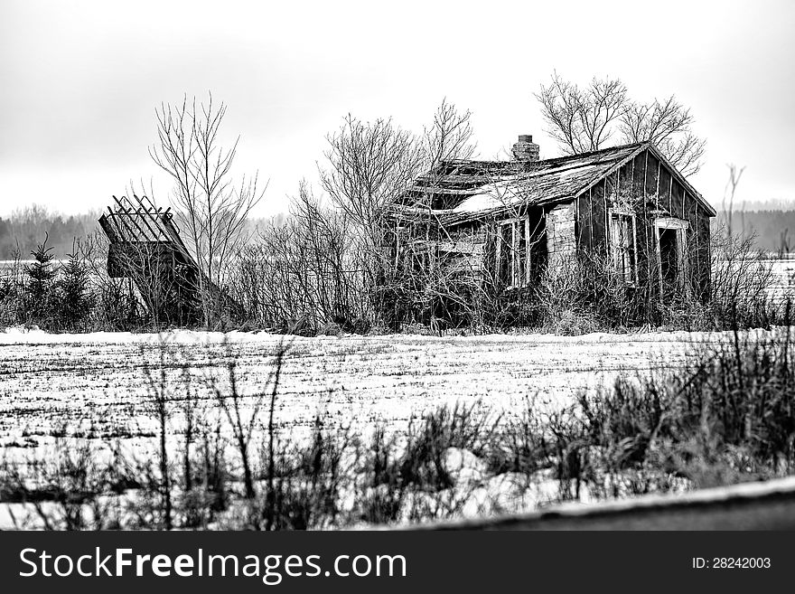 An old decaying shack on farm land in black and white.