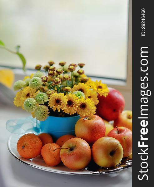 On a white background ripe apples, mandarin bright bouquet of autumn flowers in the window. On a white background ripe apples, mandarin bright bouquet of autumn flowers in the window