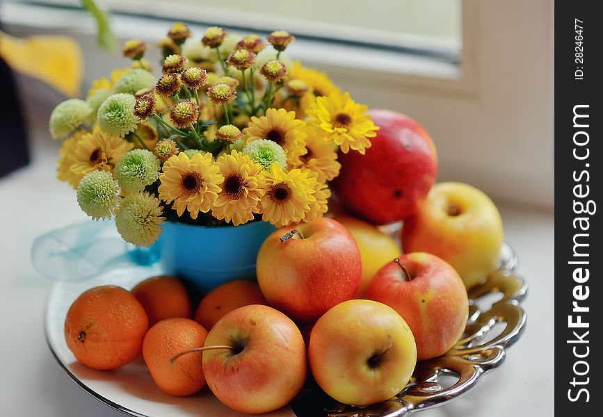 On a white background ripe apples, mandarin bright bouquet of autumn flowers in the window. On a white background ripe apples, mandarin bright bouquet of autumn flowers in the window