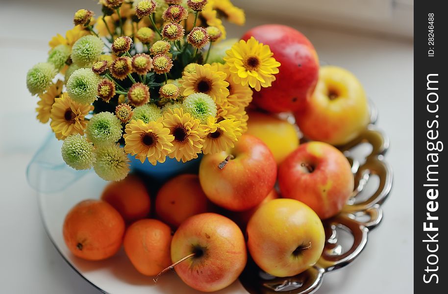 On a white background ripe apples, mandarin bright bouquet of autumn flowers in the window. On a white background ripe apples, mandarin bright bouquet of autumn flowers in the window